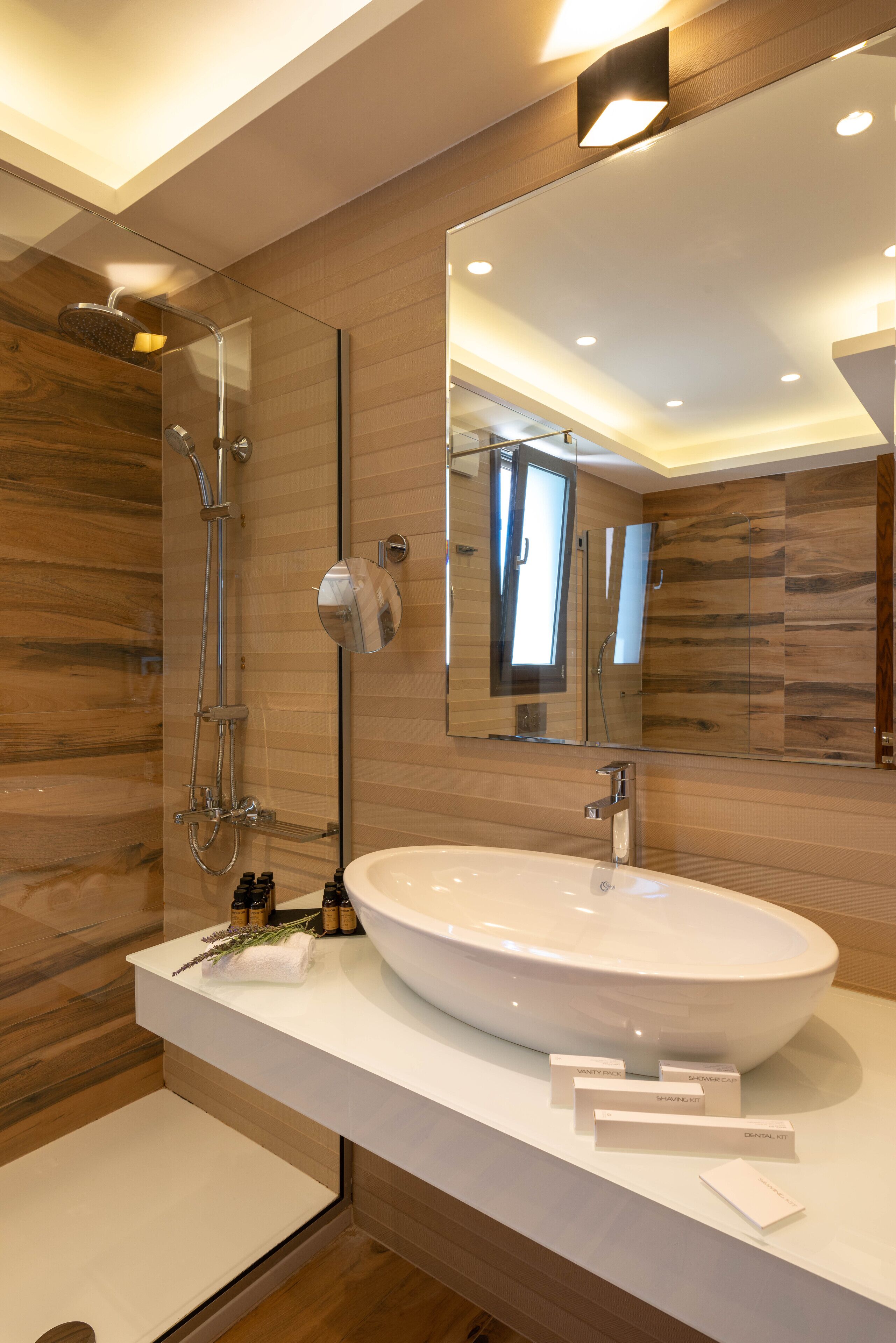A modern bathroom with a large mirror, a white sink, and a shower.