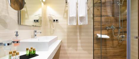 Un baño moderno con un espejo grande, un lavamanos y una ducha con mampara de vidrio.