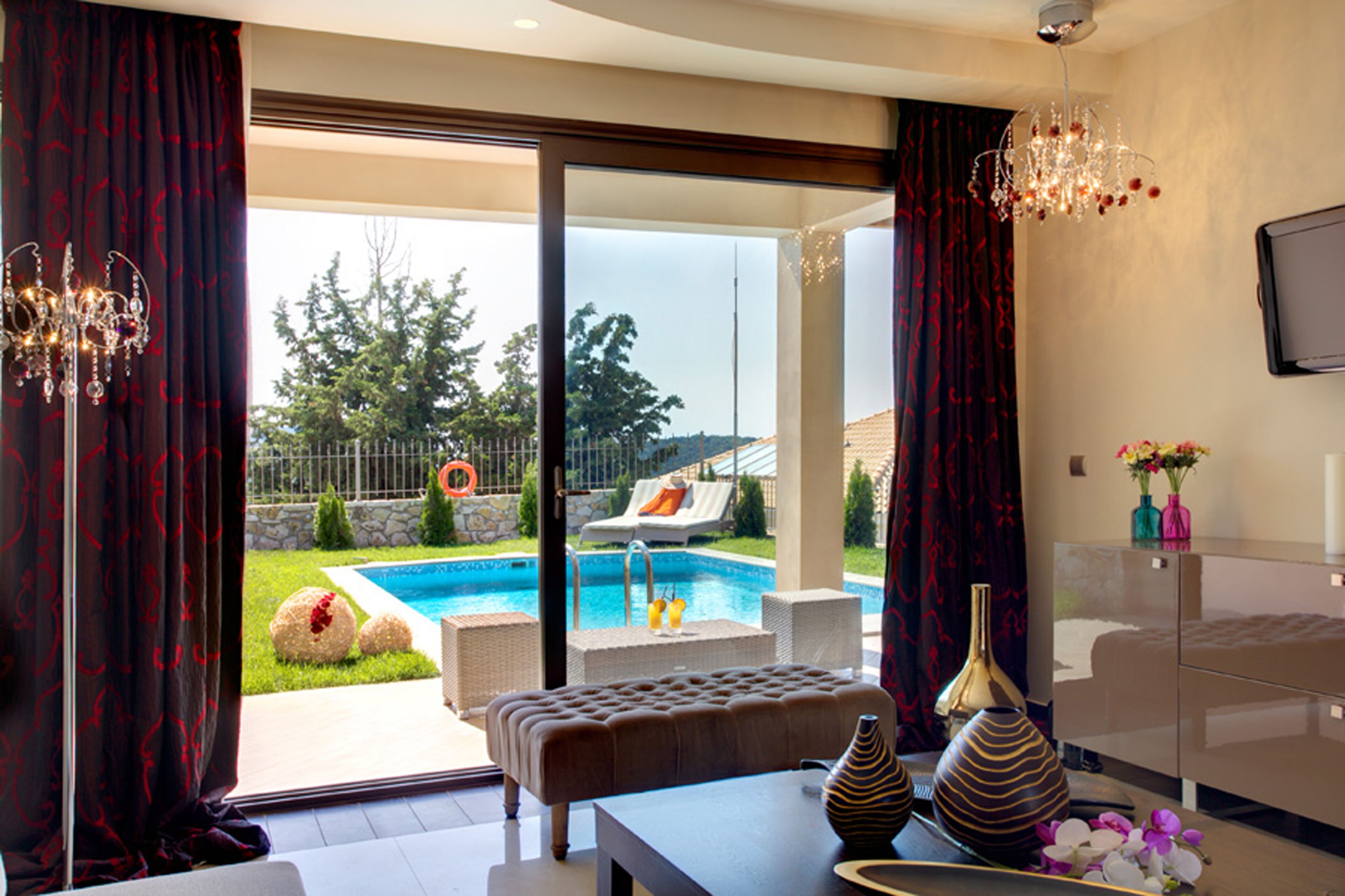 A modern living room with a pool view, a comfortable seating area, and a glass cabinet.