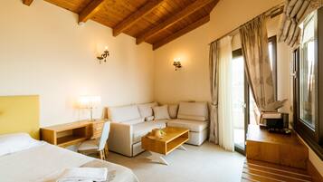 Una habitación de hotel moderna con techo de madera, un sofá, una cama, un escritorio y un ventanal con cortinas.