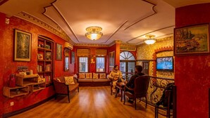 Una habitación cálidamente iluminada con pisos de madera, paredes rojas y un área de descanso con un sofá y sillones.