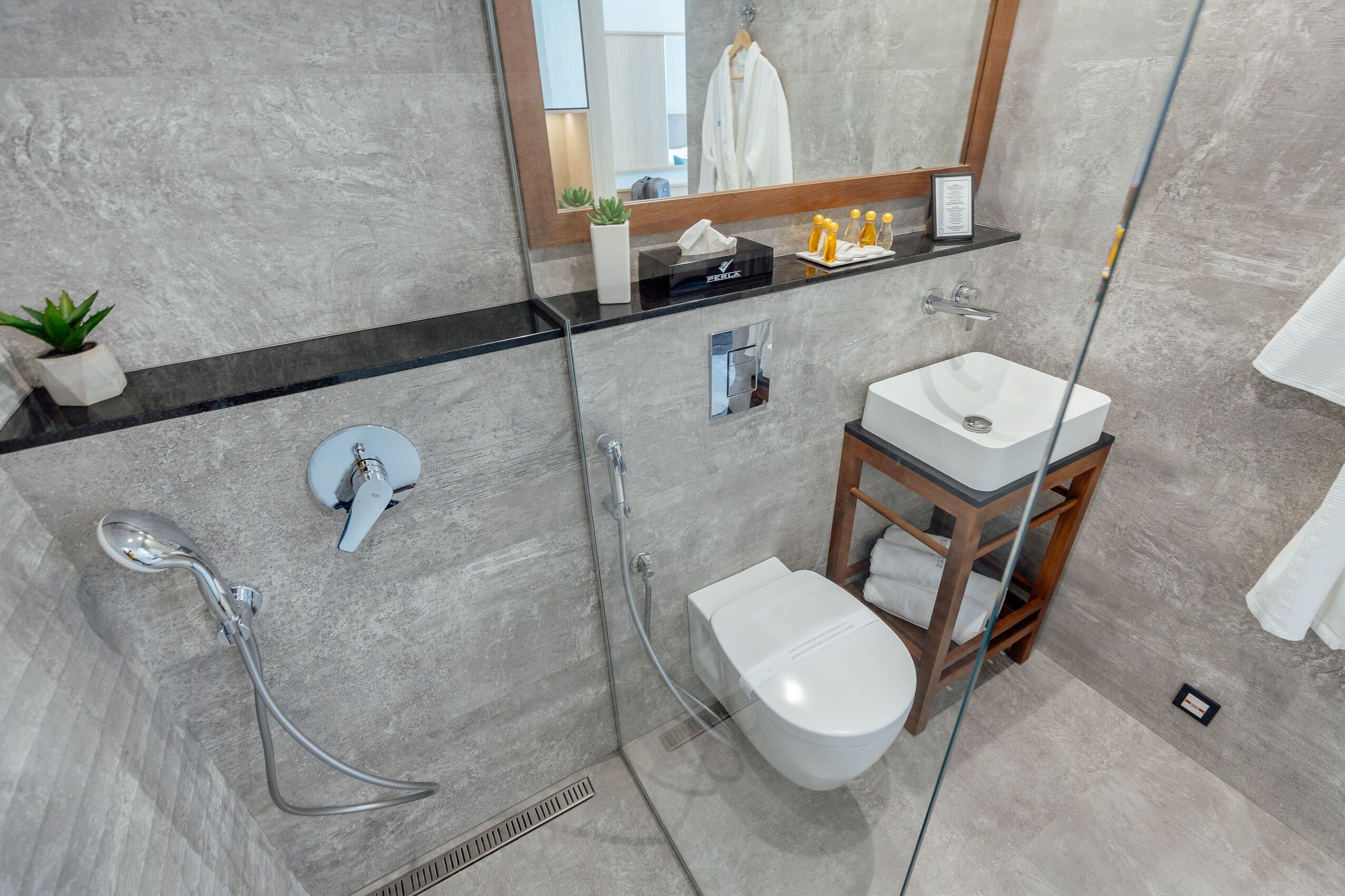 A modern bathroom with a glass-enclosed shower, a white sink, and a wooden vanity.