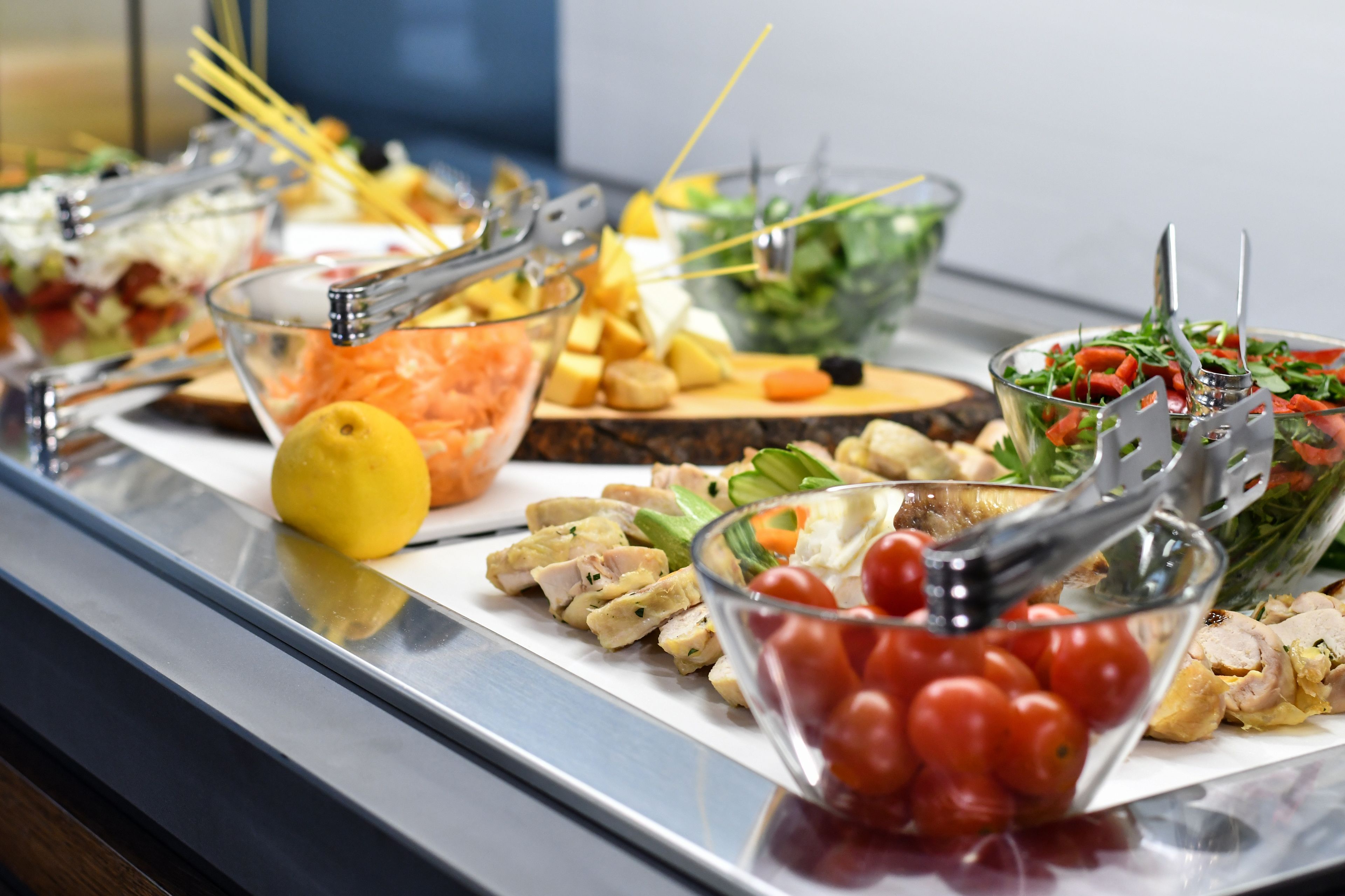 Un bufé con diversas opciones de comida, como ensaladas, frutas y carnes.