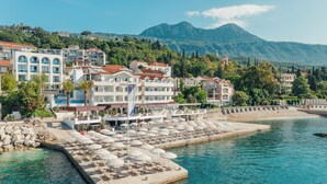 A coastal hotel with multiple balconies, a beach, and a mountain backdrop. - Hotel Perla (Herceg Novi)