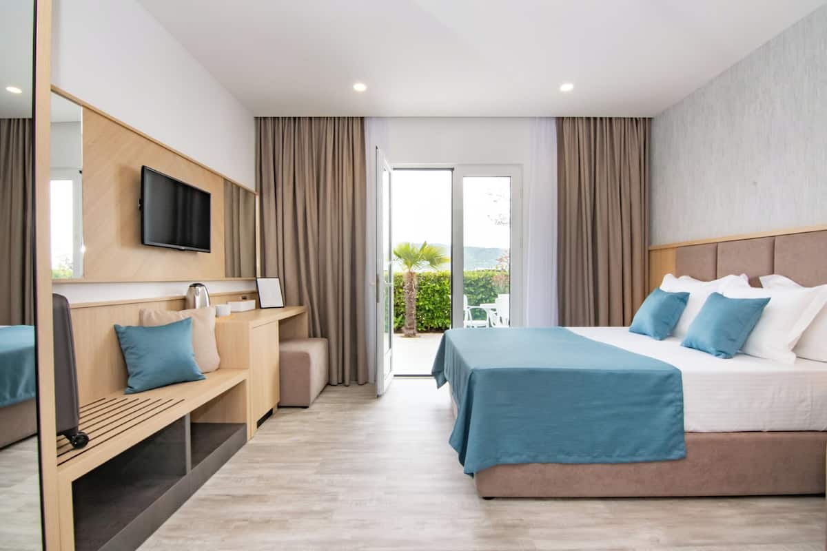 A modern hotel room with a bed, a desk, a television, and a view of the outdoors.