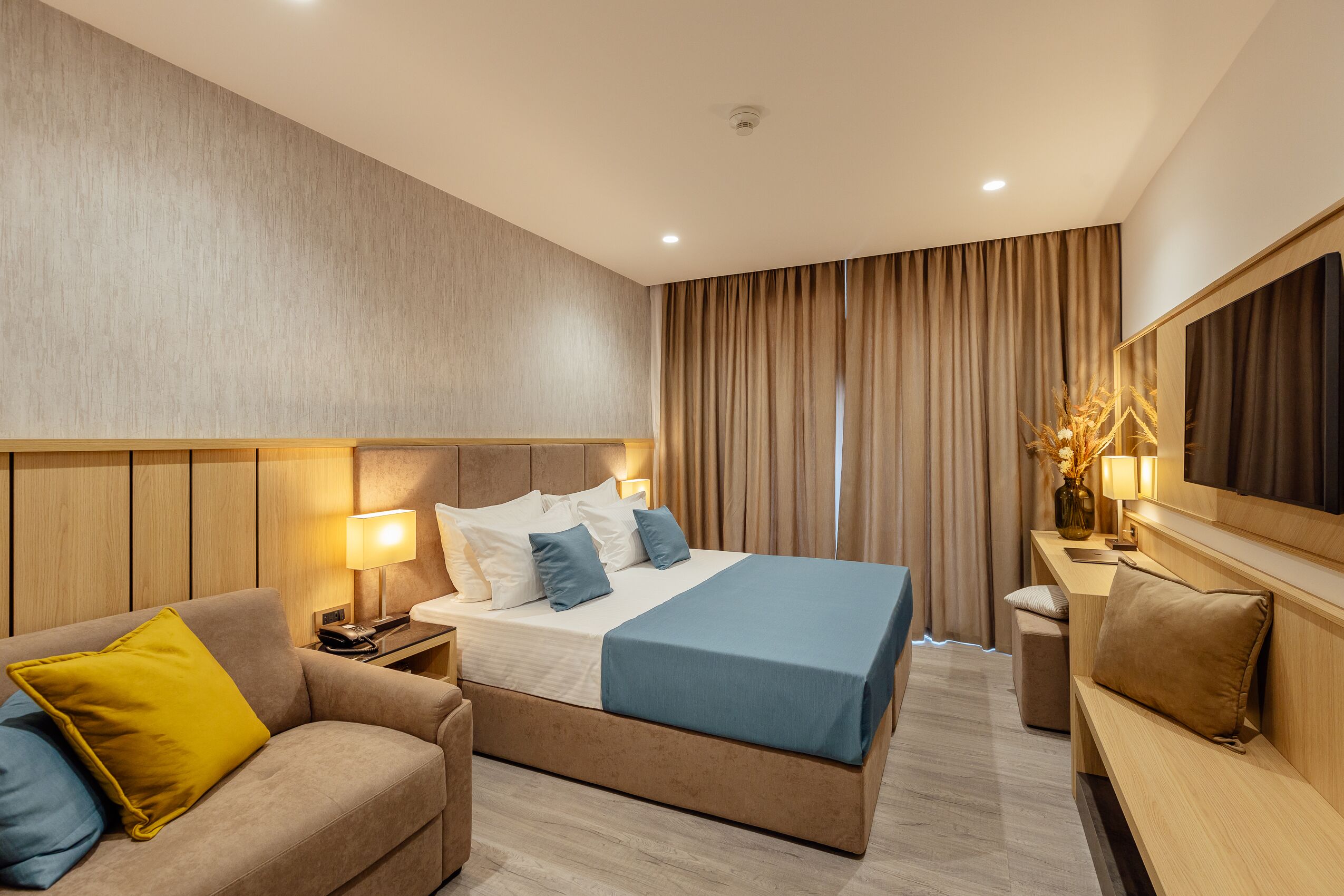Une chambre d’hôtel moderne avec un grand lit, un canapé, une table de chevet et un miroir.