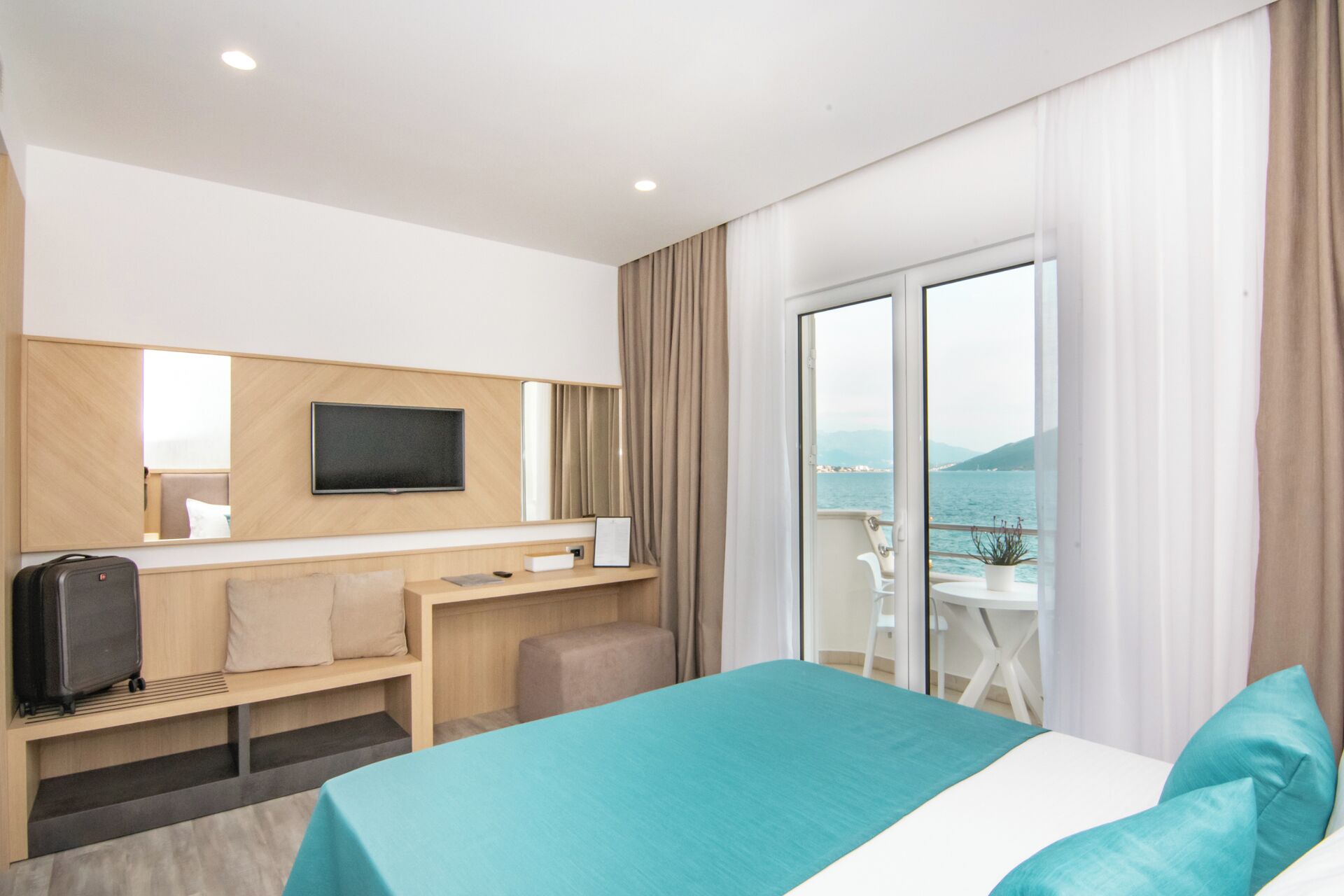 Une chambre d’hôtel moderne équipée d’un lit, d’un bureau, d’une télévision et offrant une vue sur la mer.