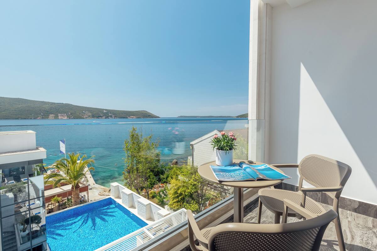 A balcony with a pool, chairs, and a table with a potted plant.