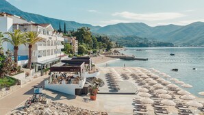 A coastal hotel with a beach, a pool area, and mountain views. - Hotel Perla (Herceg Novi)