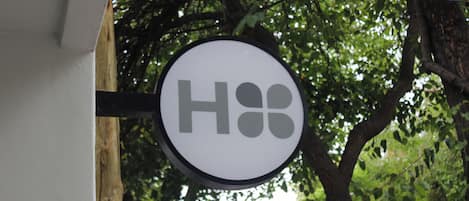 A sign with the letters "H&B" against a backdrop of trees.