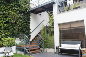 A modern outdoor staircase with metal railings, a bench, and a wicker basket. - Abril Hotel Boutique (Mendoza)