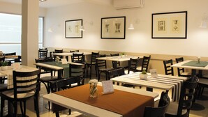 Un restaurante con varias mesas y sillas, obras de arte enmarcadas en las paredes y un equipo de aire acondicionado.