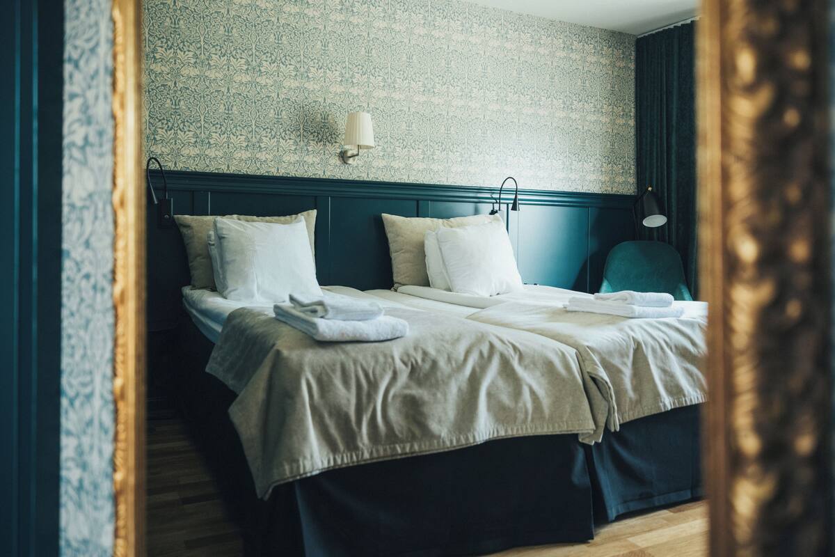 A double bed with a headboard, two bedside tables, and a wall-mounted lamp.