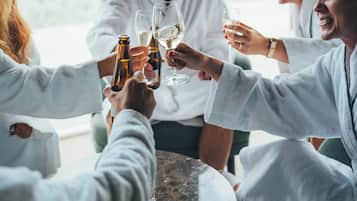 A group of people toasting with wine glasses around a table with a view of a lake.