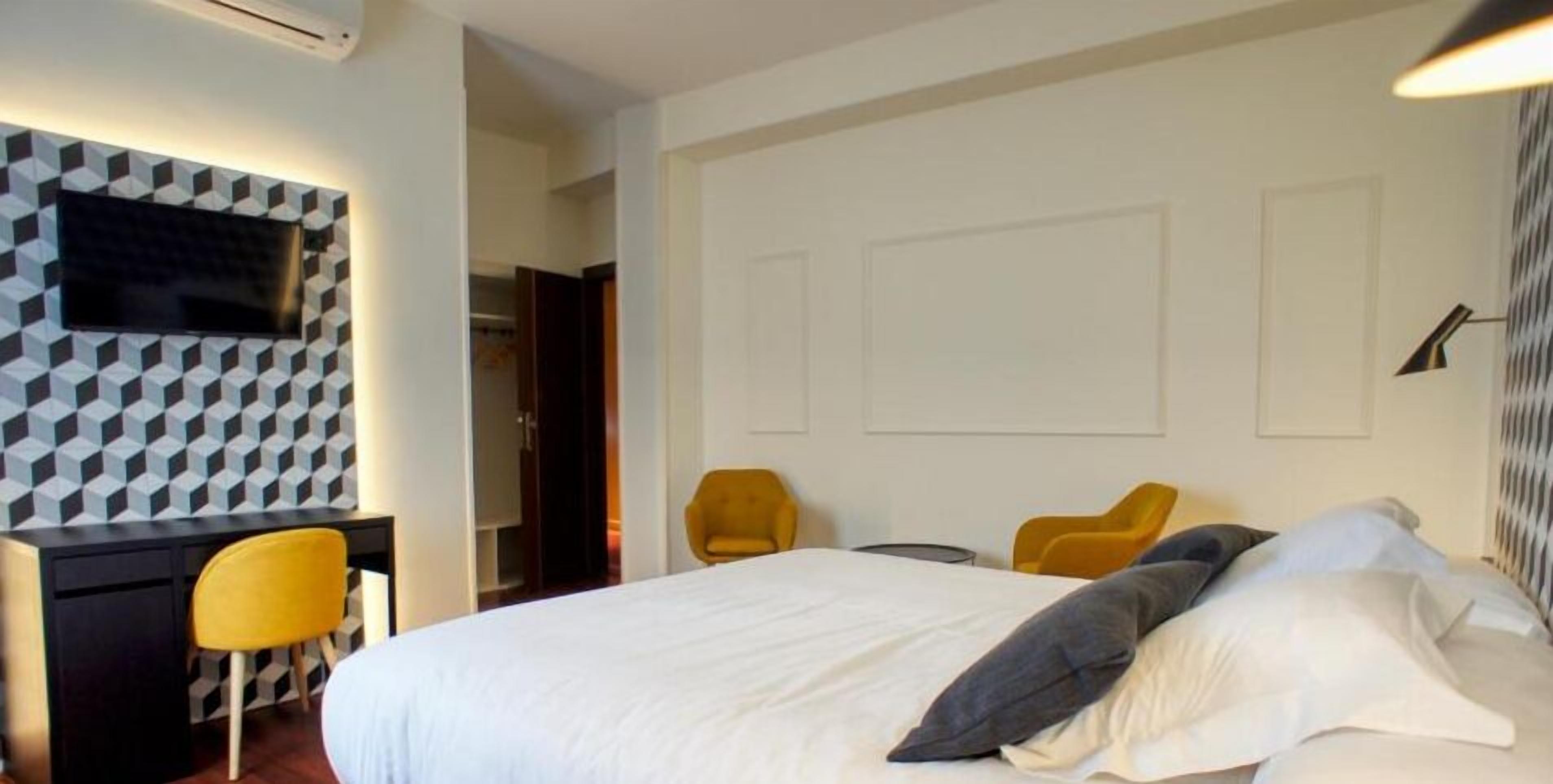 A hotel room with a bed, a desk, and two chairs.