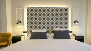 Ein Hotelzimmer mit einem Bett, zwei Nachttischen, einer Lampe und einem gemusterten Kopfteil.