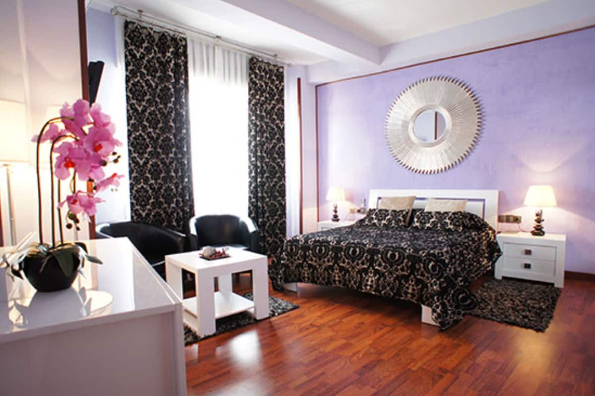 A modern bedroom with a large bed, a desk, and a chair.