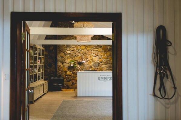 A reception area with a stone wall, a white reception desk labeled "EMPIRE," and a hanging horse riding equipment.