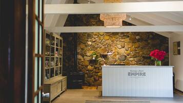 Un área de recepción con pared de piedra, una mesa de recepción con la señalización “Boutique Hotel EMPIRE” y una lámpara colgante.