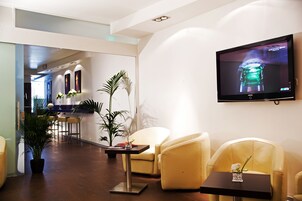 Un moderno vestíbulo de hotel con una televisión de pantalla plana, asientos cómodos y plantas en macetas.