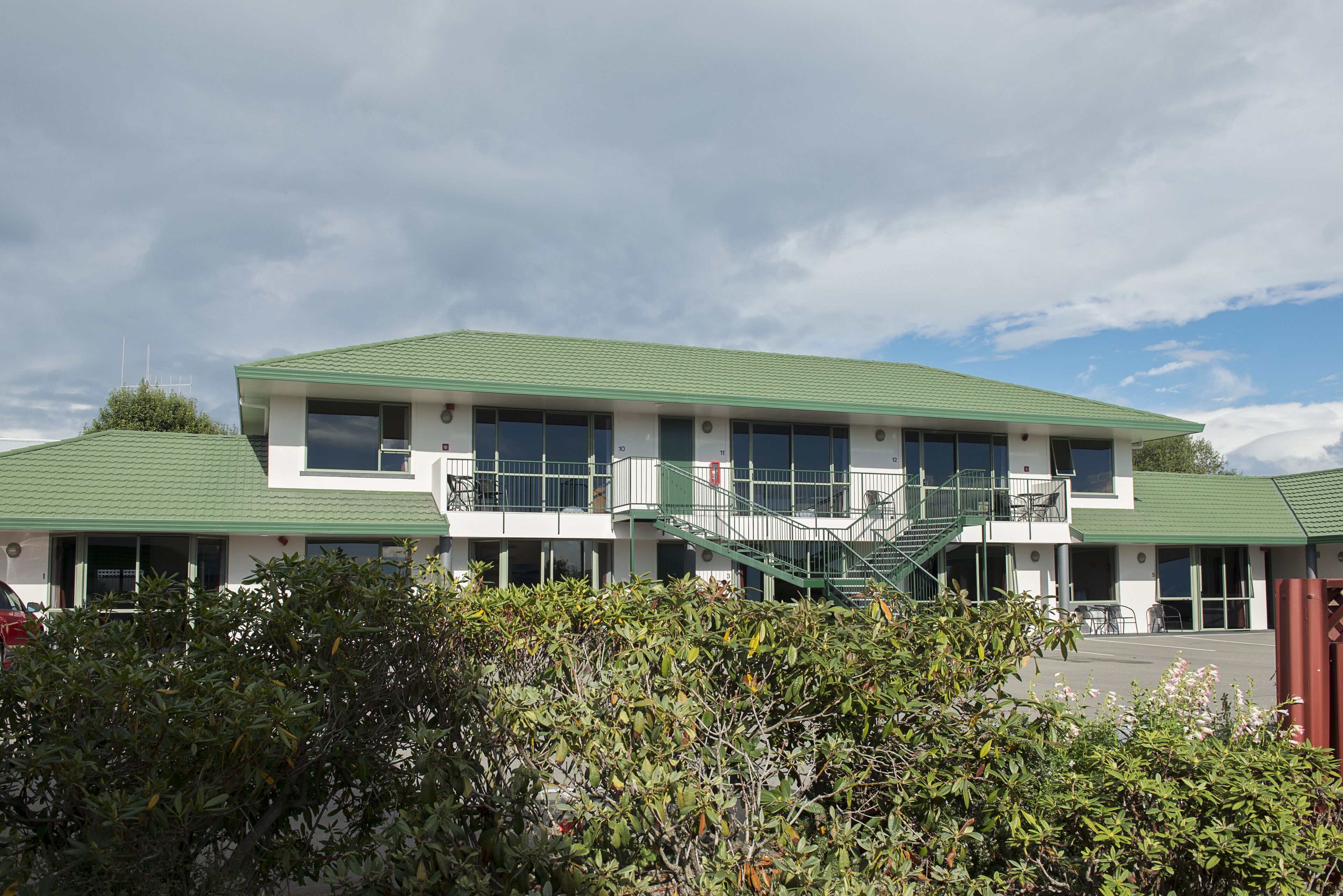 A two-story building with a green roof, large windows, and a staircase leading to the upper floor.