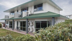 Uma casa de dois andares com varanda, janelas amplas e unidade de ar condicionado.