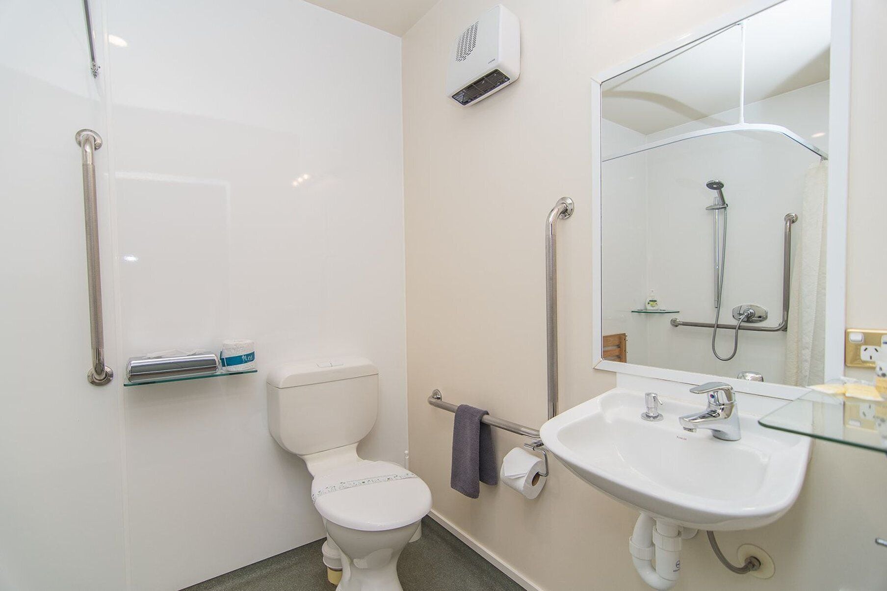 A modern bathroom with a white toilet, a glass sink, and a shower with a handheld showerhead.
