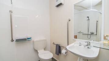 A modern bathroom with a white toilet, a glass sink, and a shower with a handheld showerhead.