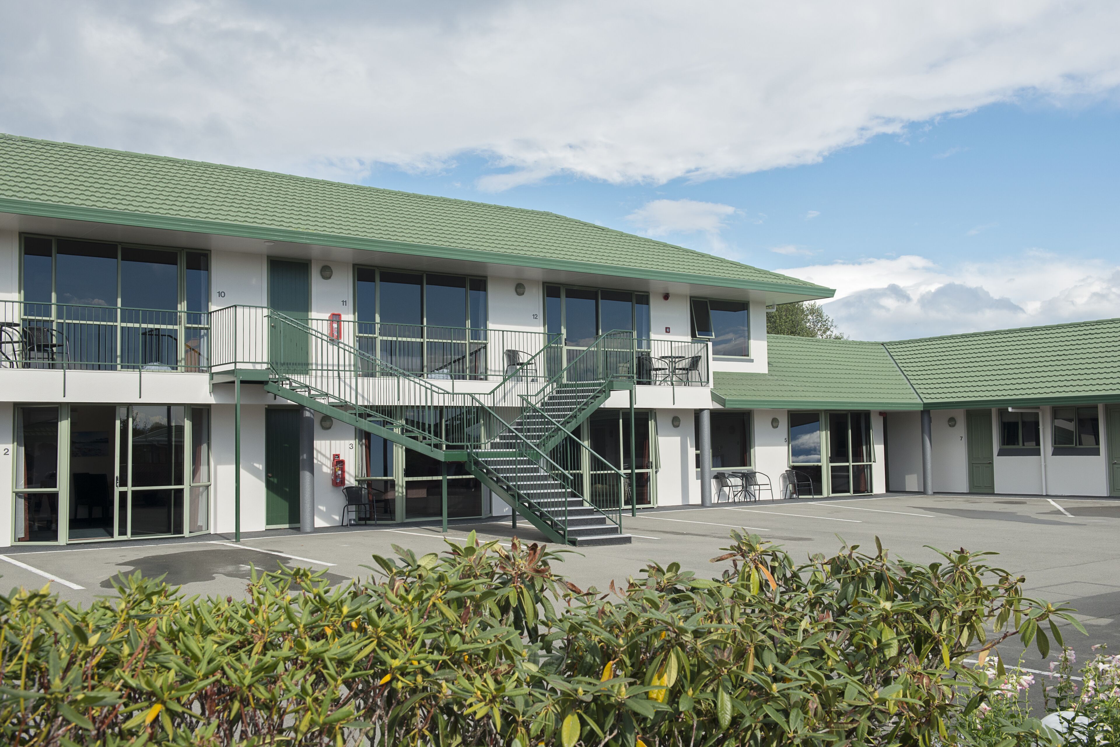 A building with a green roof, multiple windows, and a staircase leading to a balcony.