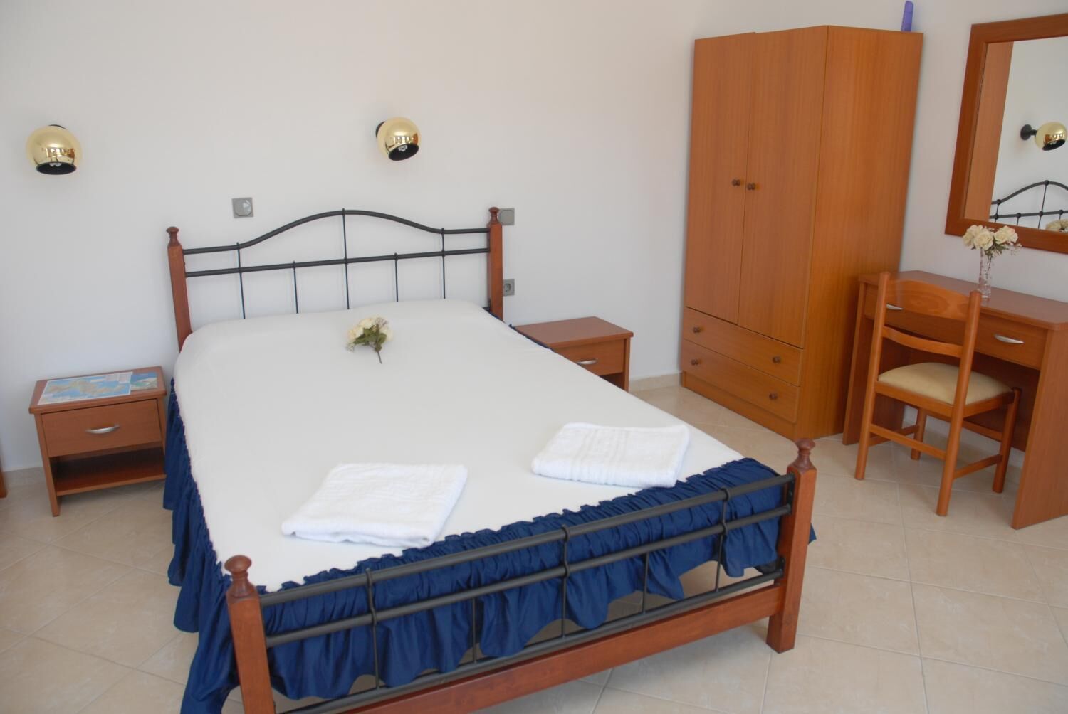 A neatly arranged bedroom with a bed, bedside tables, a wardrobe, and a desk with a chair.