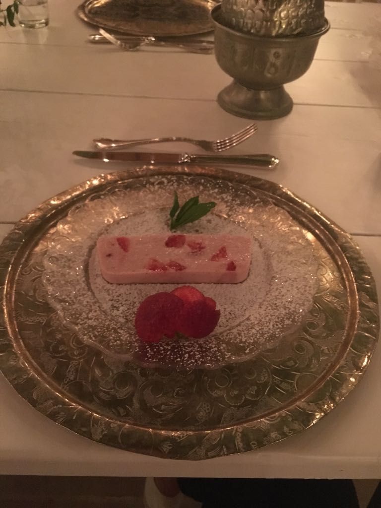 En desserttallerken med et stykke kage og en jordbær på et bord.