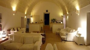 Un vaste espace de vie doté d’un haut plafond en arc de cercle, d’un escalier central et d’un coin cuisine.