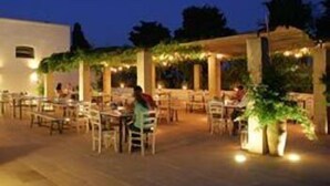 Un espace extérieur aménagé pour les repas, avec des tables et des chaises, un coin salon abrité et des plantes en pot.