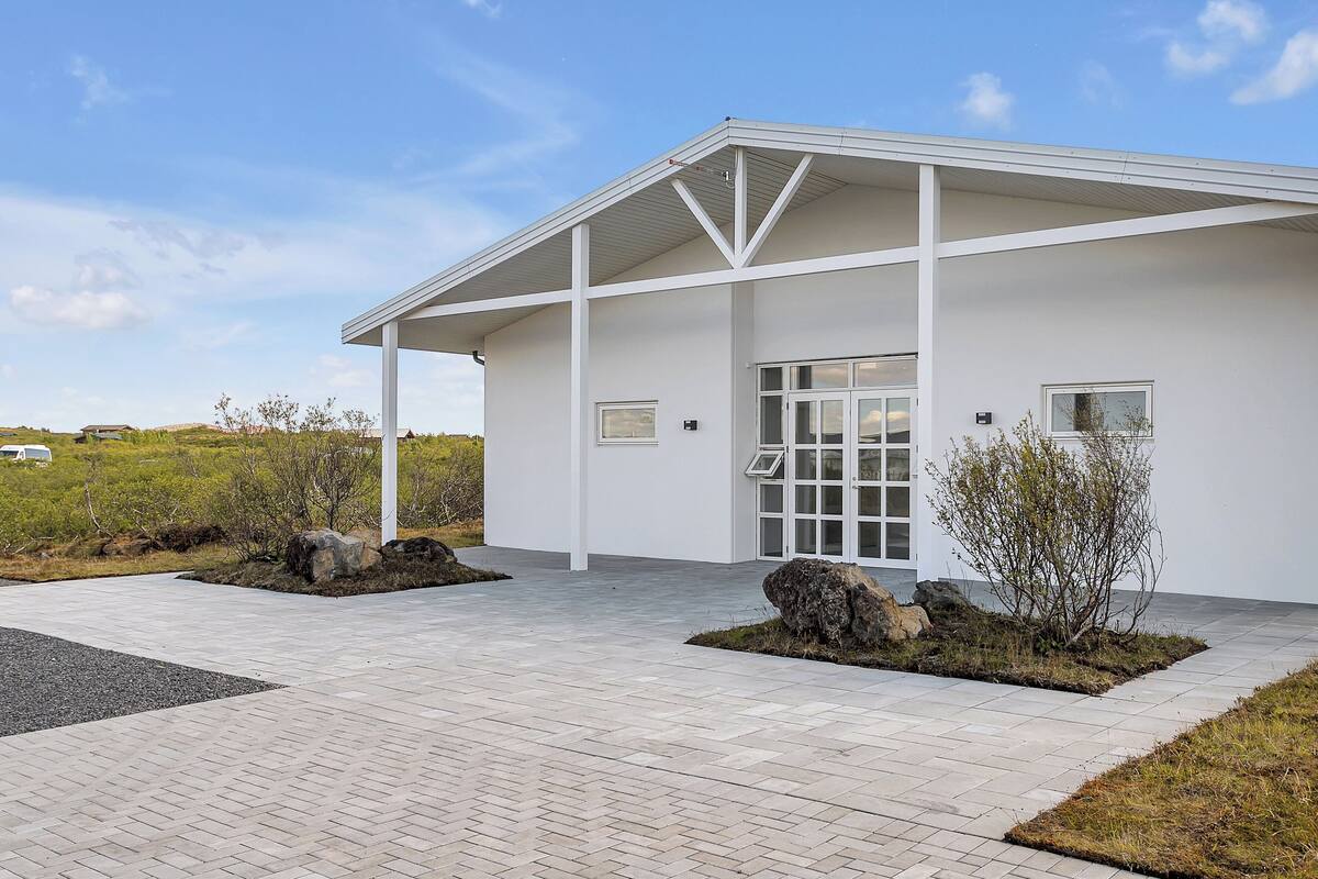 A modern building with a white exterior, large windows, and a covered entrance area.