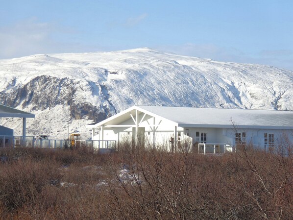 A building with a white exterior and a covered outdoor area, set against a snowy mountain backdrop.