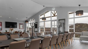 Un vaste espace de salle à manger avec de hauts plafonds et de grandes fenêtres, un mobilier moderne et une vue sur l’extérieur.