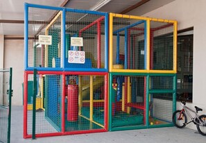 Una estructura de juego de varios niveles con señales de seguridad y una bicicleta cerca.