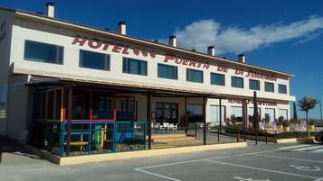 A two-story building with a sign reading "HOTEL PUERTA DE LA SERANIA".