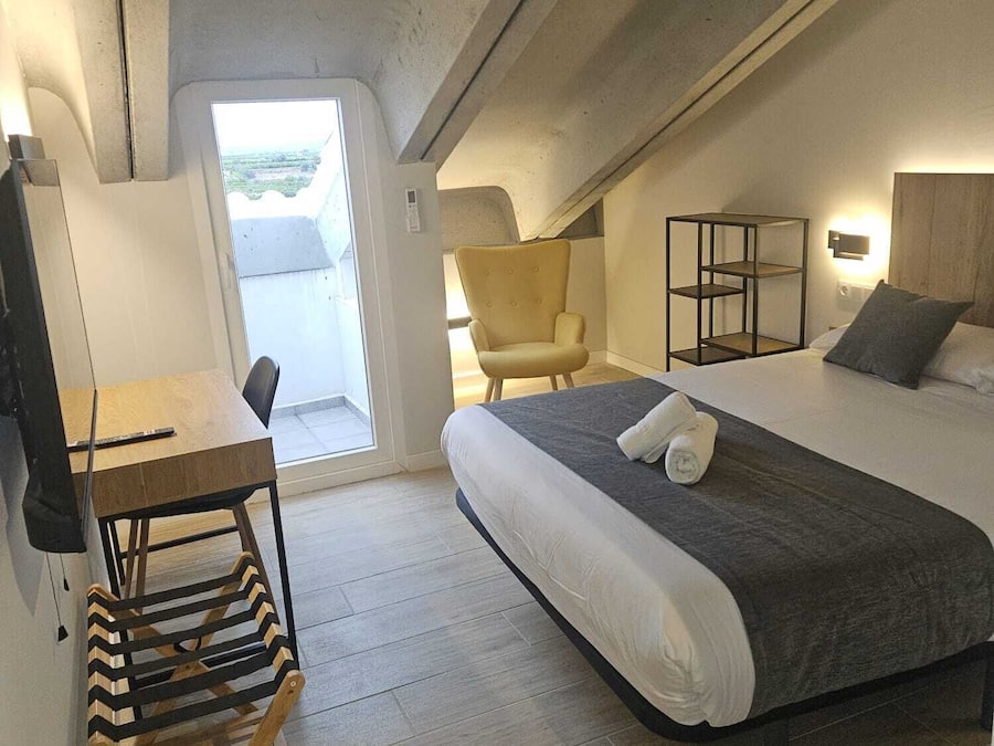 A compact room with a bed, a chair, a desk, and a small table.