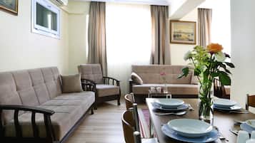 Departamento Deluxe, 2 habitaciones, planta baja | Área de sala de estar | Televisión de 82 pulgadas con canales vía satélite y reproductor de DVD