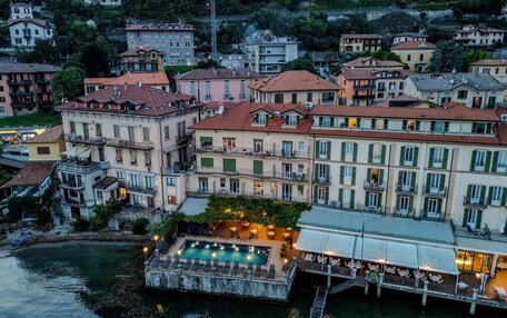 A waterfront hotel with multiple balconies, a swimming pool, and a restaurant area.