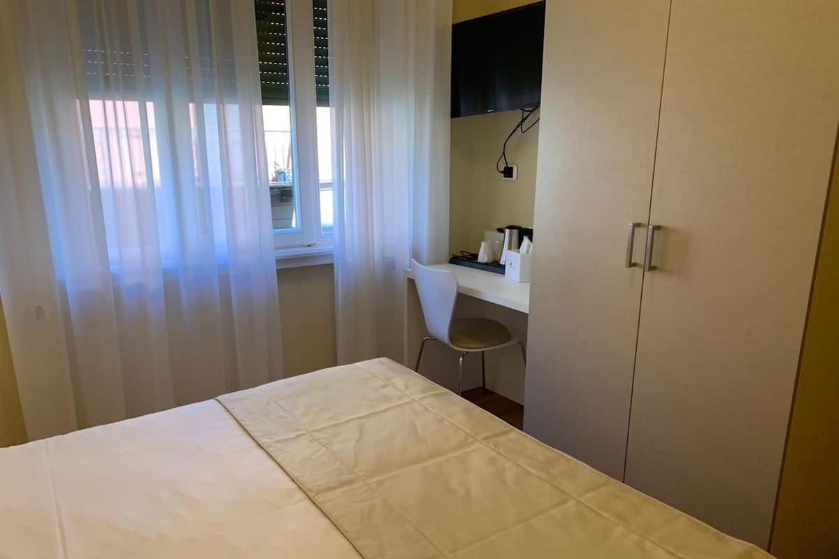 A bedroom with a bed, a desk, a chair, and a wardrobe.