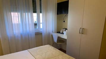 Una camera da letto con un letto, una scrivania, una sedia e un armadio.