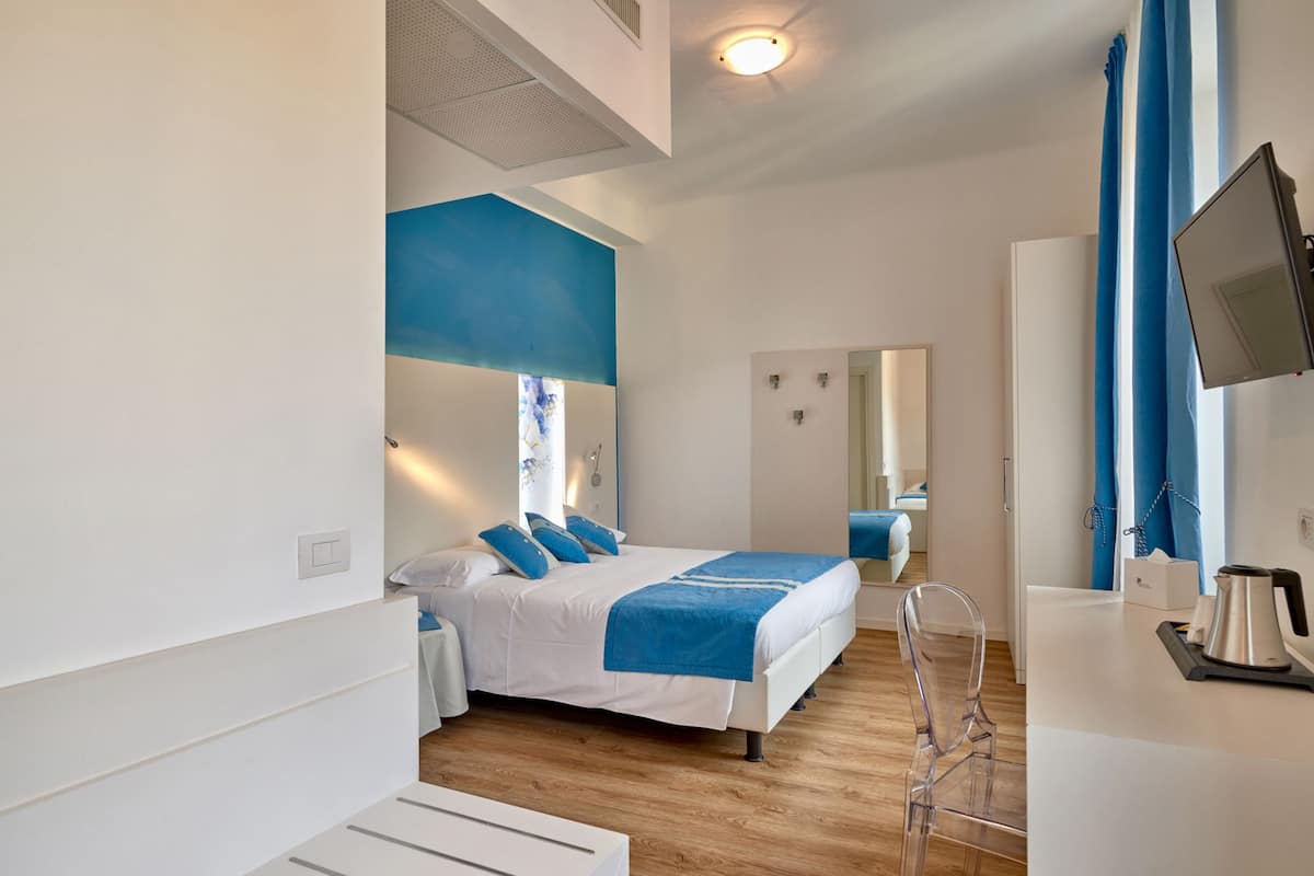 A modern hotel room with a bed, a TV, and a bathroom.
