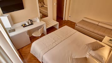 Una camera d'albergo con un letto, una scrivania con una sedia, una televisione e un angolo cottura.