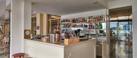 A modern bar area with a polished wooden floor, a central bar counter, and a glass partition.