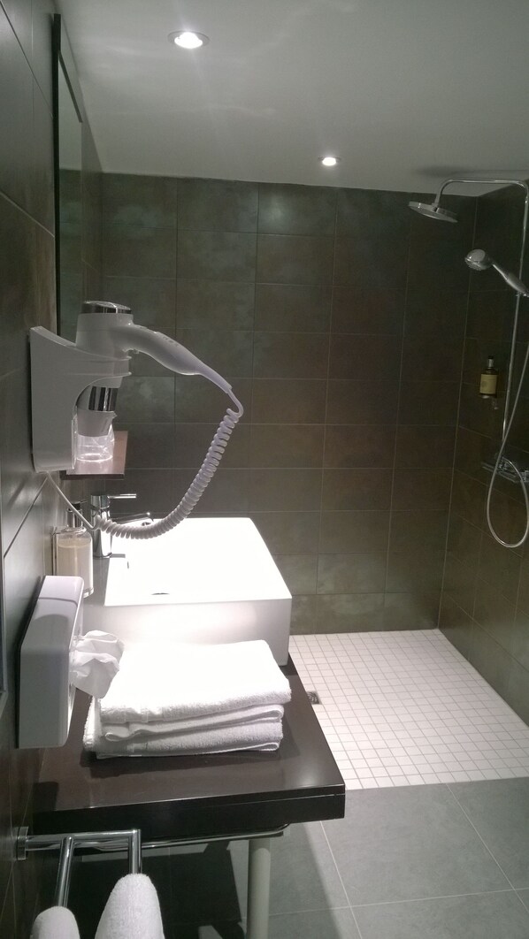 A modern bathroom with a shower, a towel rack, and a sink with a mirror.