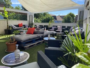 An outdoor patio area with a covered seating area, a small table, and potted plants. - Cour du Tonnelier (Bouxwiller)
