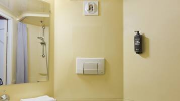Een badkamer met een wastafel, spiegel, handdoekhouder, douche en een zeepdispenser.