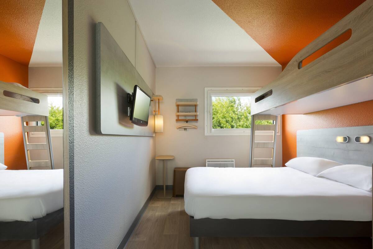 A modern room with bunk beds, a flat-screen TV, a window with a view, and a small table.